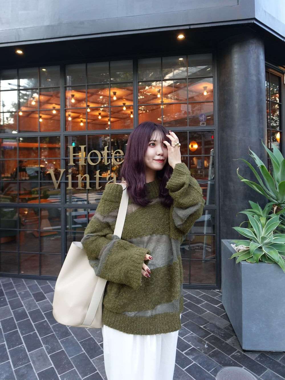 グリーン系のニット/セーター、ホワイト系のスラックス、シルバー系のローファーを着用したレディースの秋コーディネートの5枚目の写真