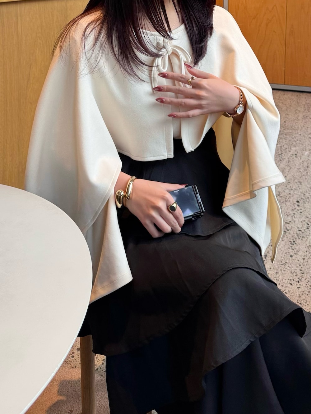 ベージュ系のトップス、ブラック系のスカート、ブラック系のパンプスを着用したレディースの春コーディネートの4枚目の写真