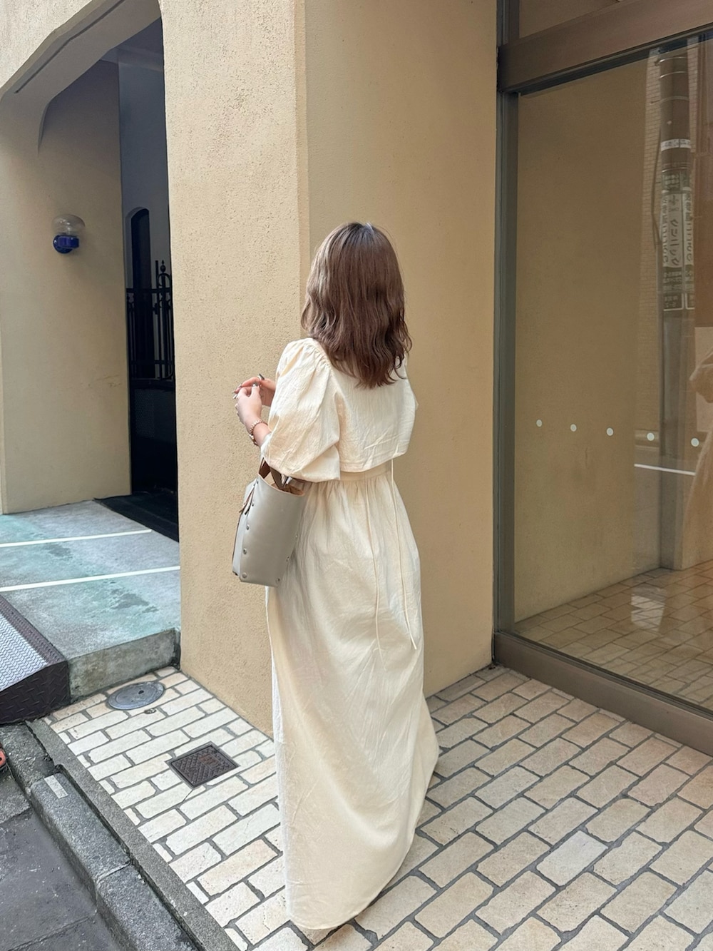 ベージュ系のハンドバッグ、ホワイト系のワンピース、ベージュ系のサンダルを着用したレディースの夏コーディネートの2枚目の写真