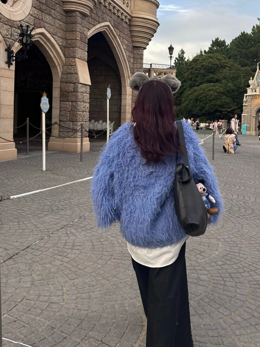 ブラック系のショルダーバッグ、ブルー系のニット/セーター、ブラック系のデニムパンツを着用したレディースの秋コーディネートの5枚目の写真