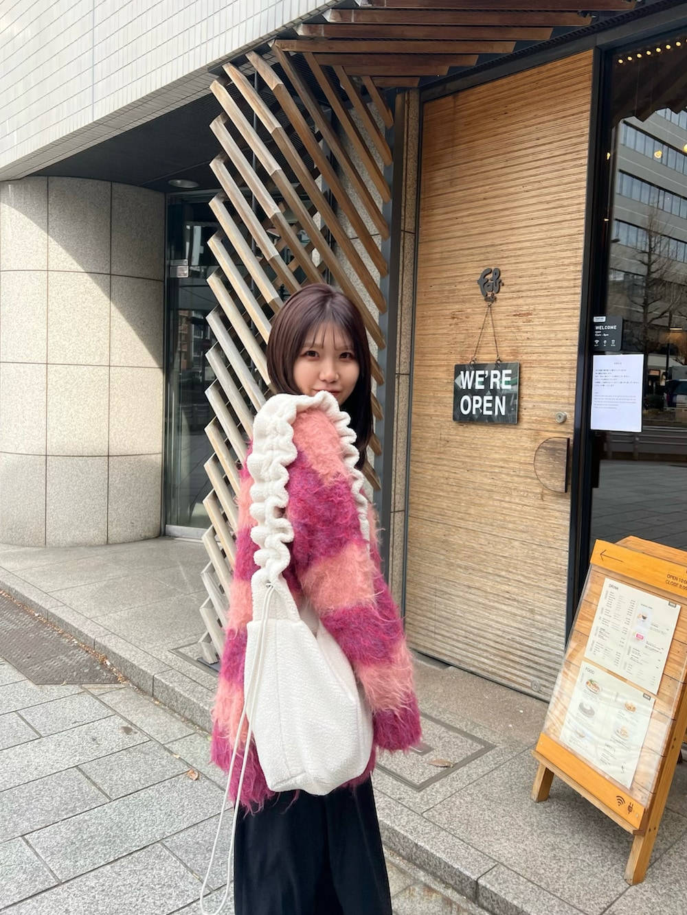 レッド系のカーディガン/ボレロ、ブラック系のワンピース/ドレス、レッド系のバレエシューズを着用したレディースの冬コーディネートの3枚目の写真