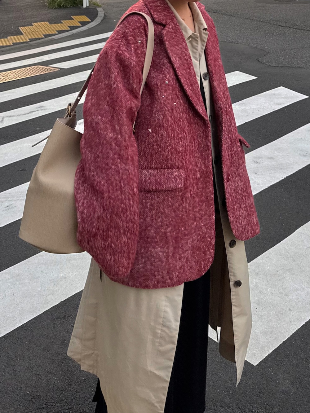 ベージュ系のステンカラーコート、ブラック系のブーツ、ベージュ系のショルダーバッグを着用したレディースの秋コーディネートの3枚目の写真