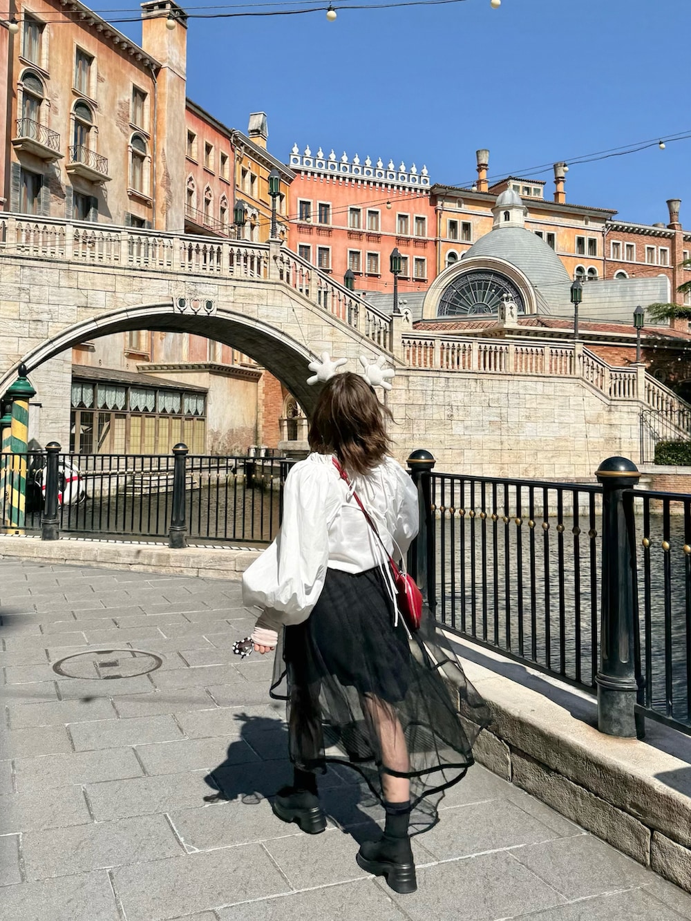 ブラック系のスカート、レッド系のバッグ、ホワイト系のシャツ/ブラウスを着用したレディースの夏コーディネートの3枚目の写真