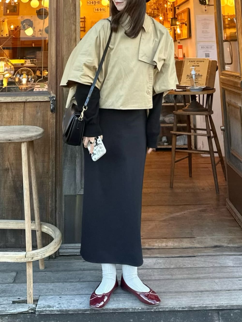 ベージュ系のトレンチコート、ブラック系のショルダーバッグ、ブラック系のスカートを着用したレディースの冬コーディネートの3枚目の写真