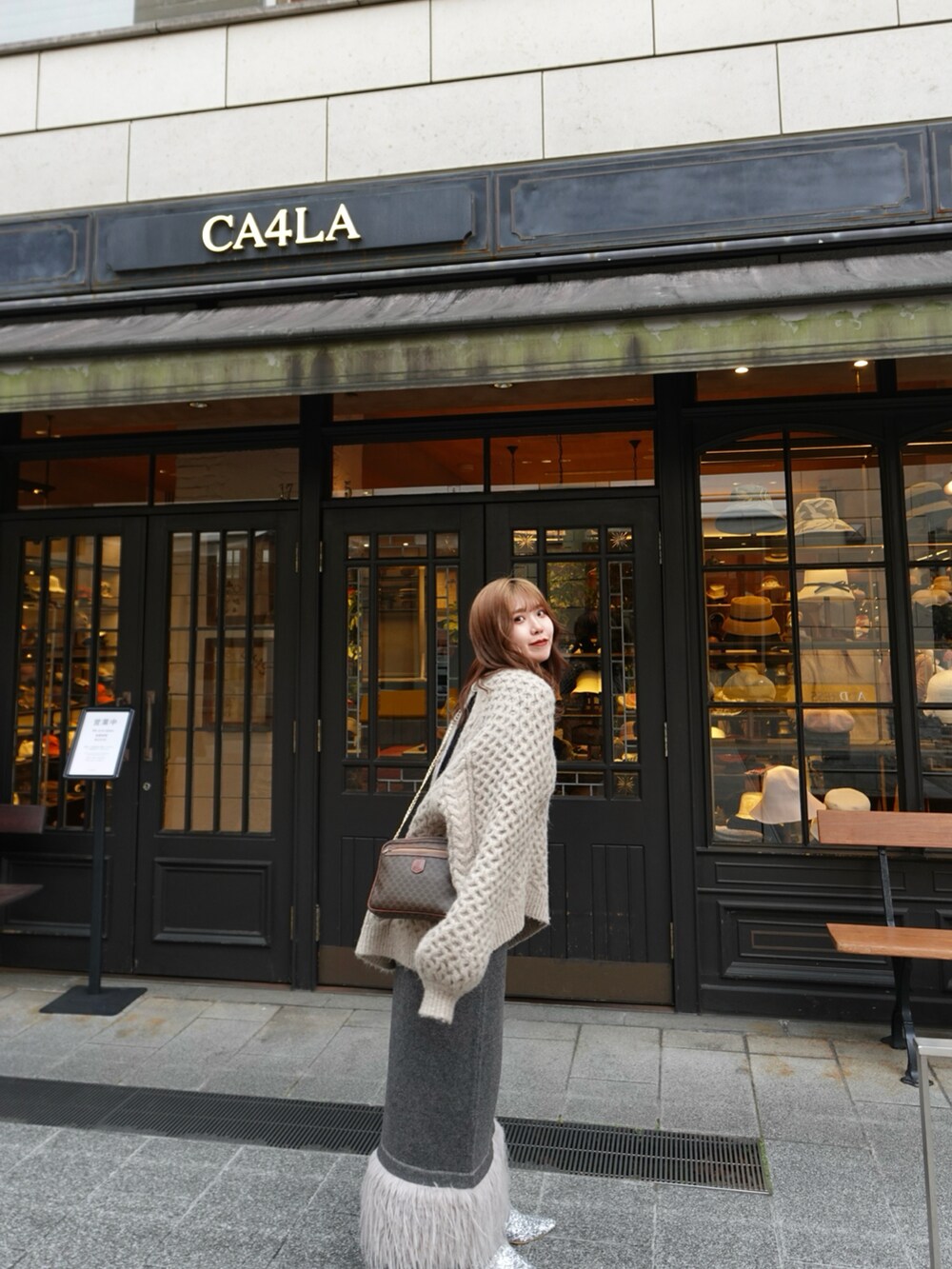 グレー系のスカート、ブラウン系のニット/セーター、シルバー系のローファーを着用したレディースの春コーディネートの4枚目の写真