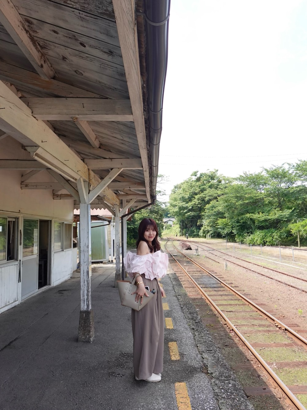 ベージュ系のハンドバッグ、ピンク系のシャツ/ブラウス、ブラウン系のパンツを着用したレディースの夏コーディネートの4枚目の写真