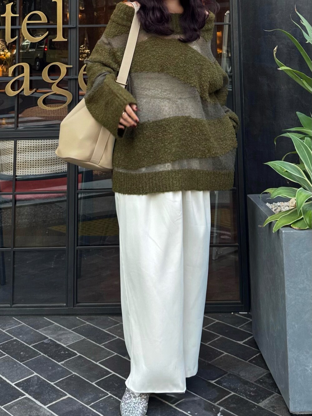 グリーン系のニット/セーター、ホワイト系のスラックス、シルバー系のローファーを着用したレディースの秋コーディネートの2枚目の写真