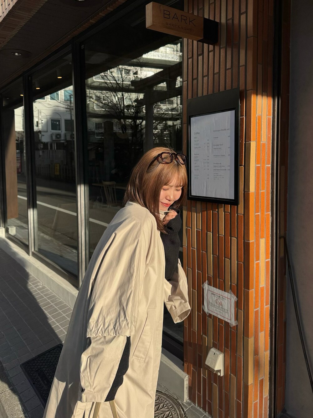 ベージュ系のショルダーバッグ、ベージュ系のステンカラーコート、ブラック系のワンピースを着用したレディースの冬コーディネートの5枚目の写真