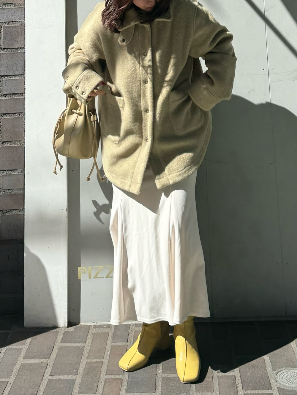 グリーン系のその他アウター、ベージュ系のショルダーバッグ、イエロー系のブーツを着用したレディースの春コーディネートの2枚目の写真