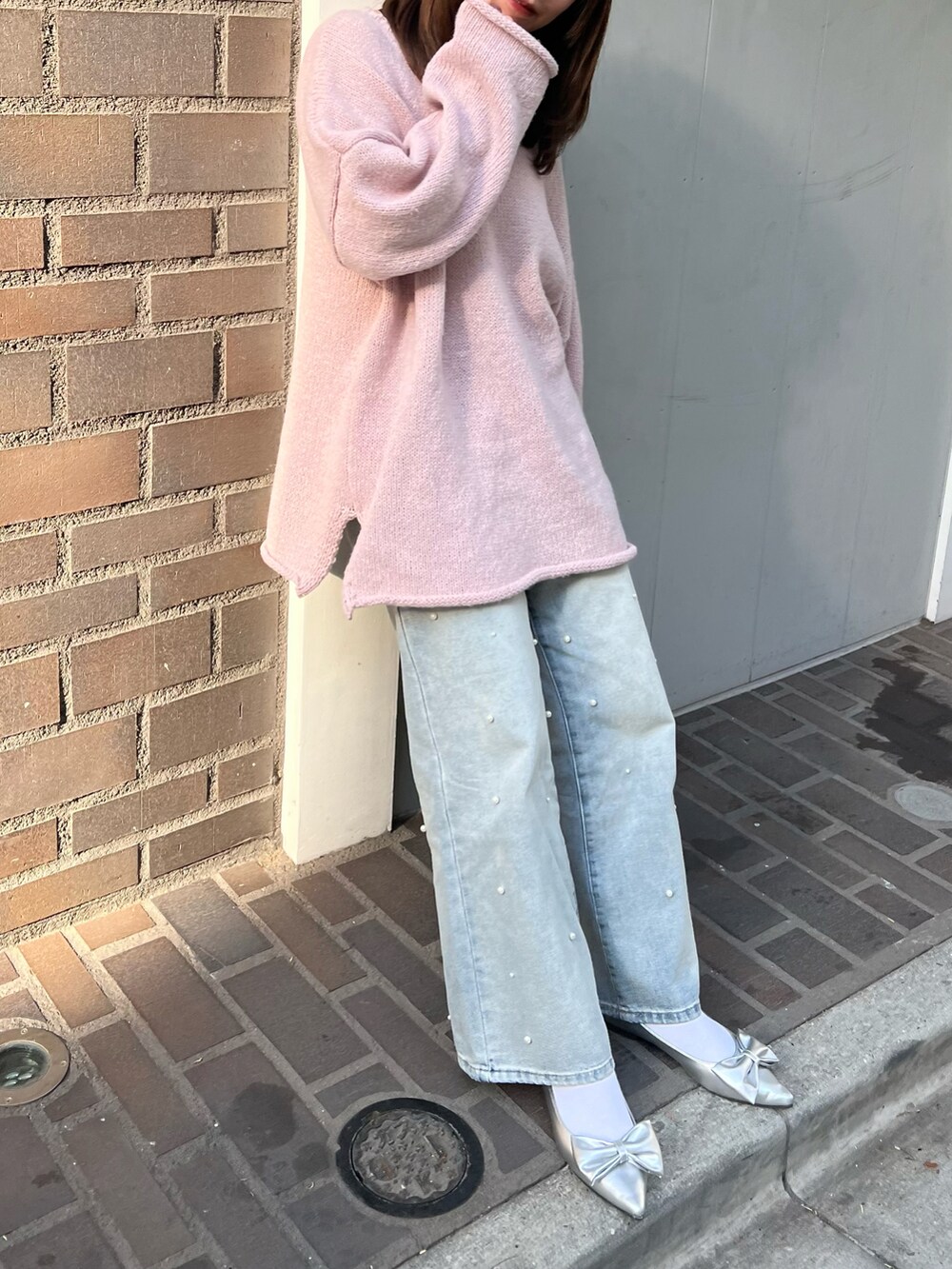 シルバー系のトートバッグ、シルバー系のパンプス、ブルー系のデニムパンツを着用したレディースの冬コーディネートの2枚目の写真