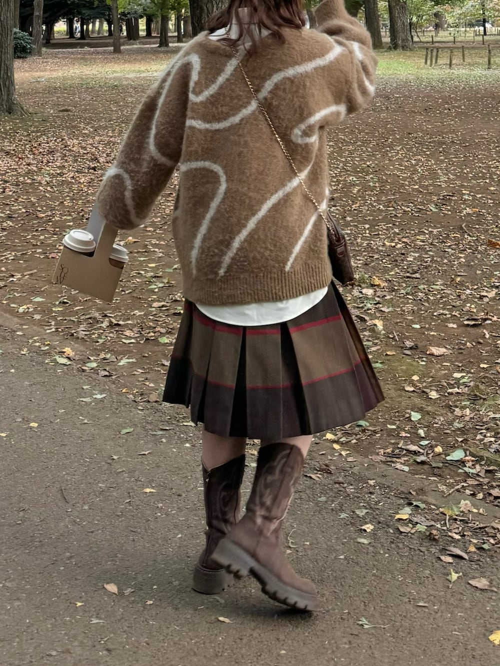 ブラウン系のニット/セーター、ブラウン系のスカート、ベージュ系のシャツ/ブラウスを着用したレディースの秋コーディネートの2枚目の写真