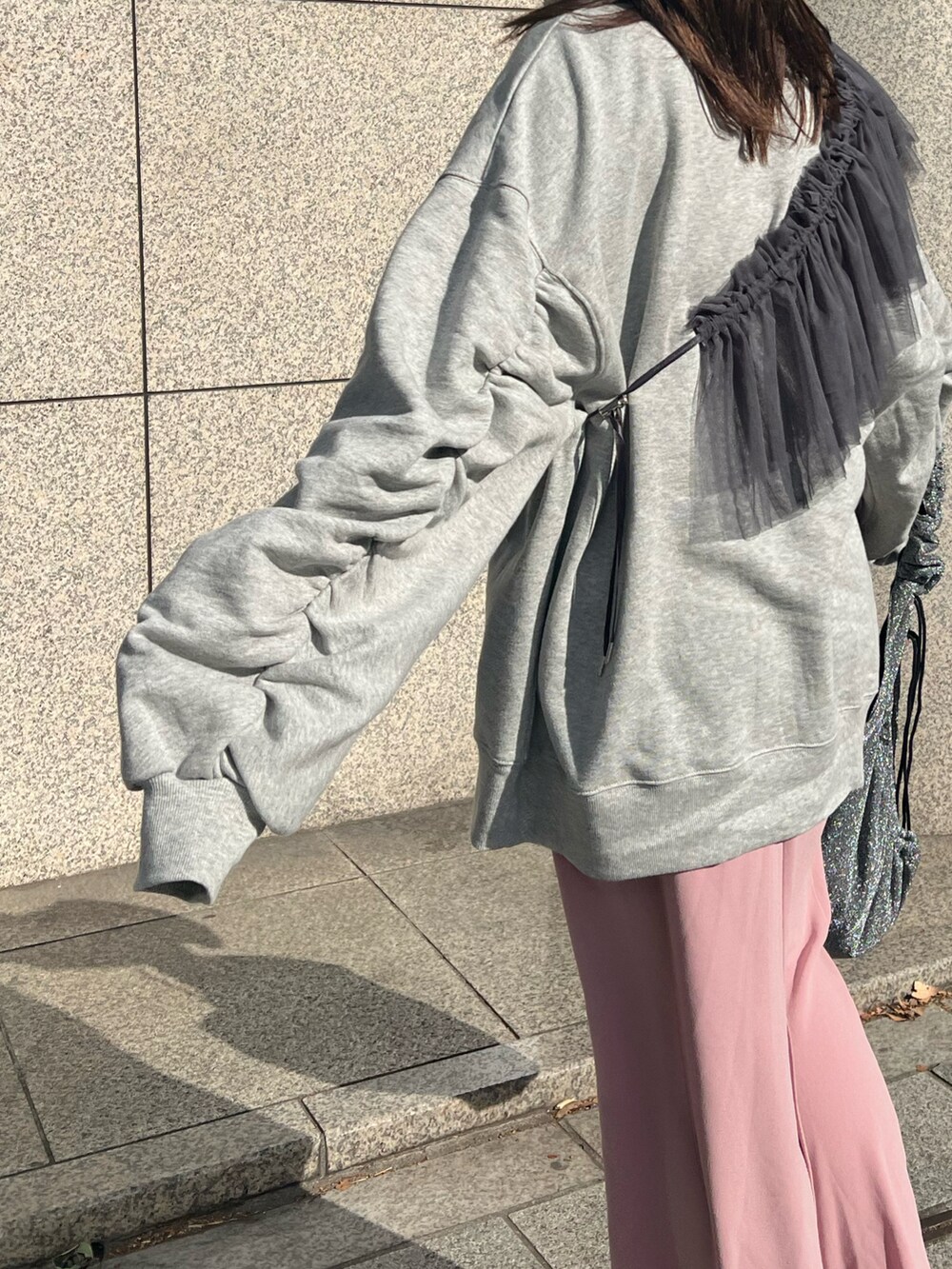 ピンク系のスカート、シルバー系のスニーカー、グレー系のスウェットを着用したレディースの冬コーディネートの3枚目の写真