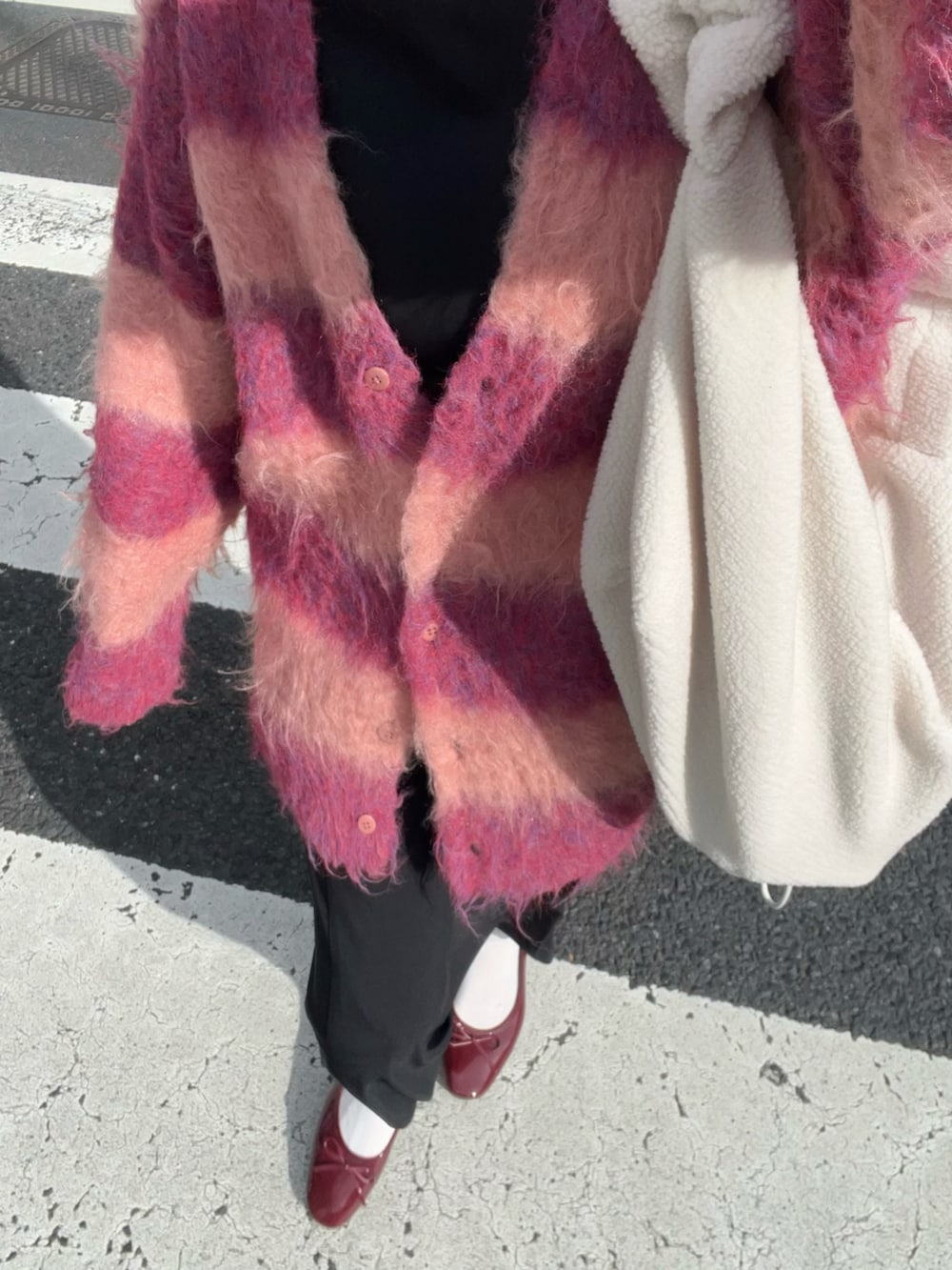 レッド系のカーディガン/ボレロ、ブラック系のワンピース/ドレス、レッド系のバレエシューズを着用したレディースの冬コーディネートの2枚目の写真