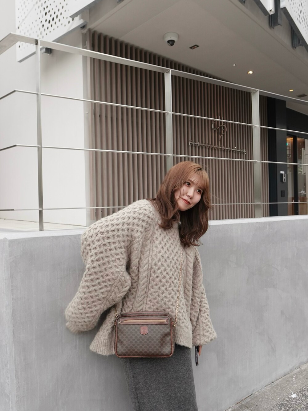 グレー系のスカート、ブラウン系のニット/セーター、シルバー系のローファーを着用したレディースの春コーディネートの5枚目の写真