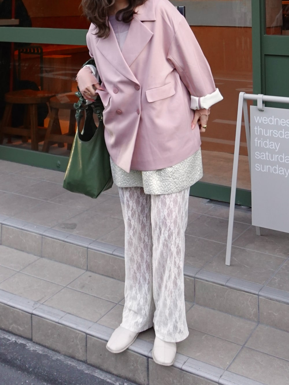 ピンク系のテーラードジャケット、ホワイト系のブーツ、グリーン系のショルダーバッグを着用したレディースの春コーディネートの2枚目の写真