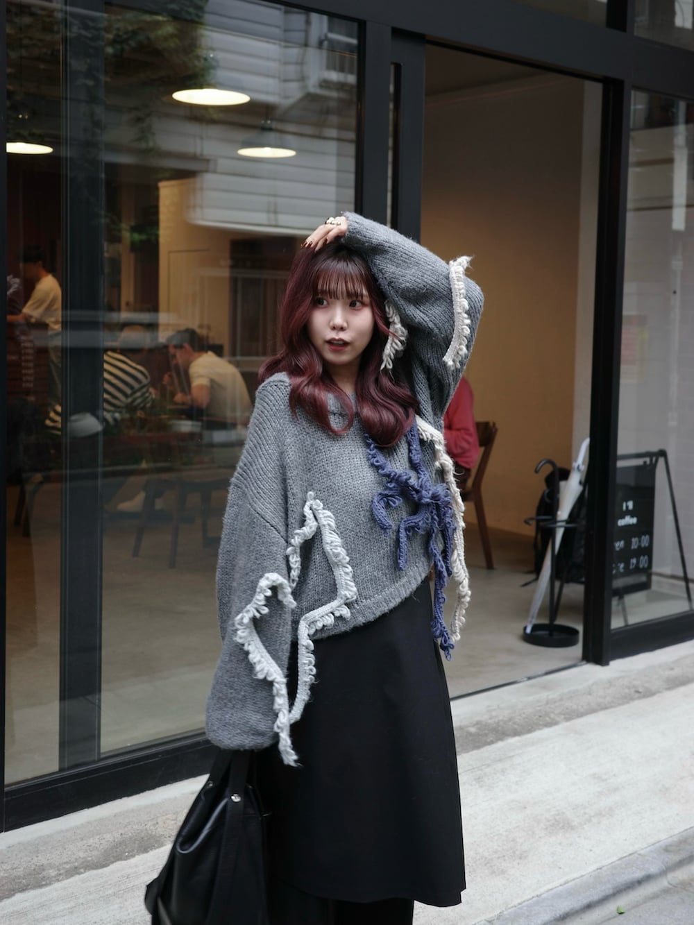 ブラック系のパンツ、ブラック系のショルダーバッグ、グレー系のニット/セーターを着用したレディースの秋コーディネートの3枚目の写真