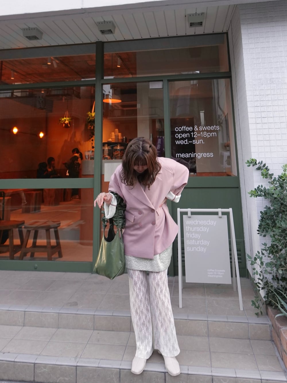 ピンク系のテーラードジャケット、ホワイト系のブーツ、グリーン系のショルダーバッグを着用したレディースの春コーディネートの3枚目の写真