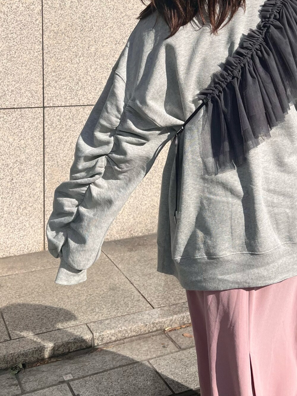 ピンク系のスカート、シルバー系のスニーカー、グレー系のスウェットを着用したレディースの冬コーディネートの2枚目の写真