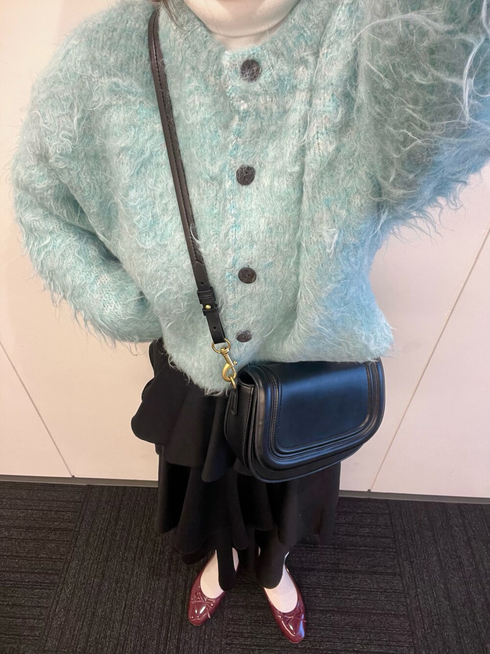 レッド系のバレエシューズ、ブラック系のショルダーバッグ、ブルー系のカーディガン/ボレロを着用したレディースの冬コーディネートの4枚目の写真