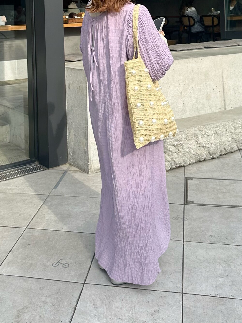 パープル系のワンピース、シルバー系のパンプス、ベージュ系のトートバッグを着用したレディースの夏コーディネートの2枚目の写真