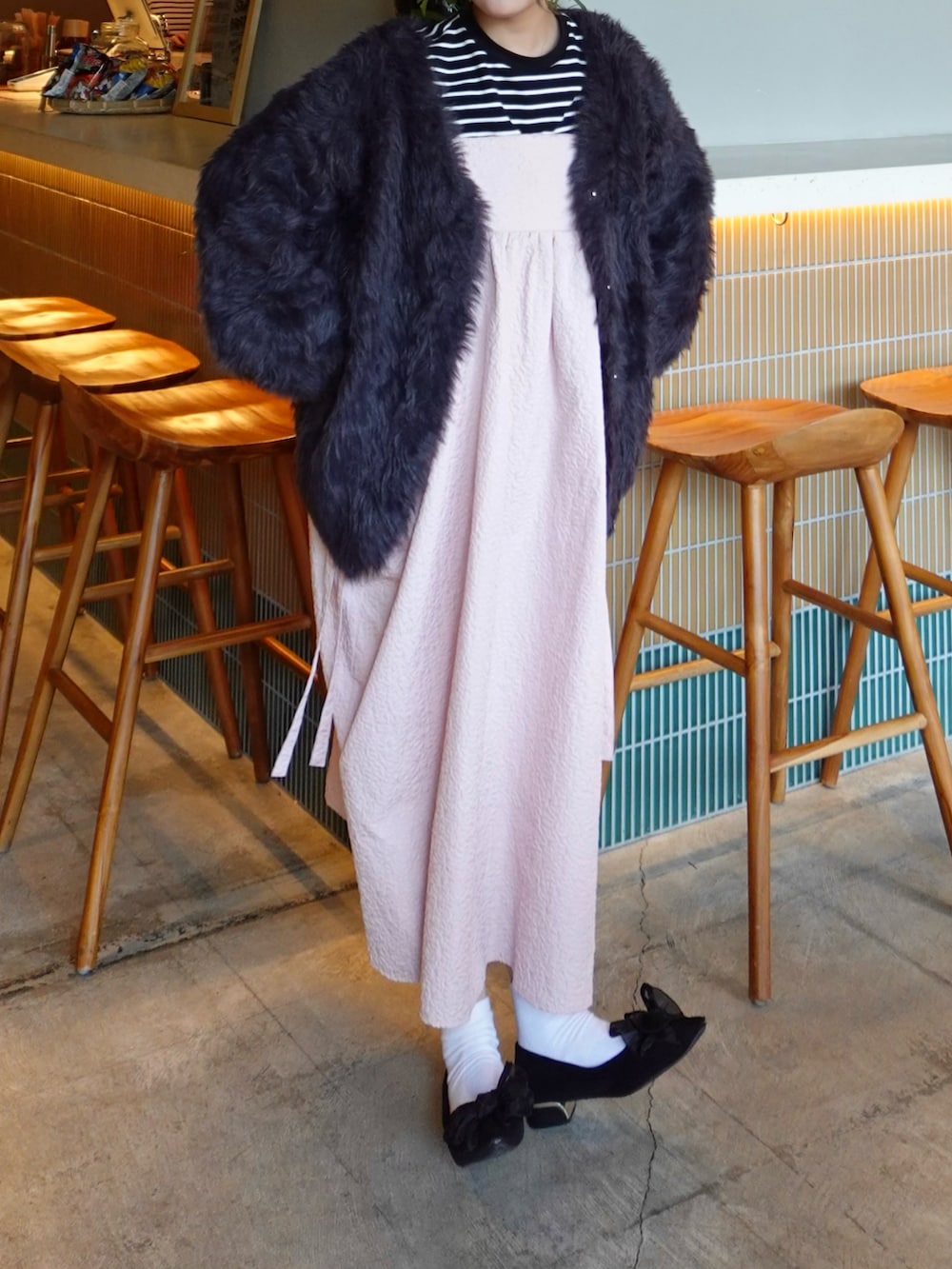 ピンク系のワンピース、ブラック系のパンプス、ブラック系のニット/セーターを着用したレディースの春コーディネートの2枚目の写真