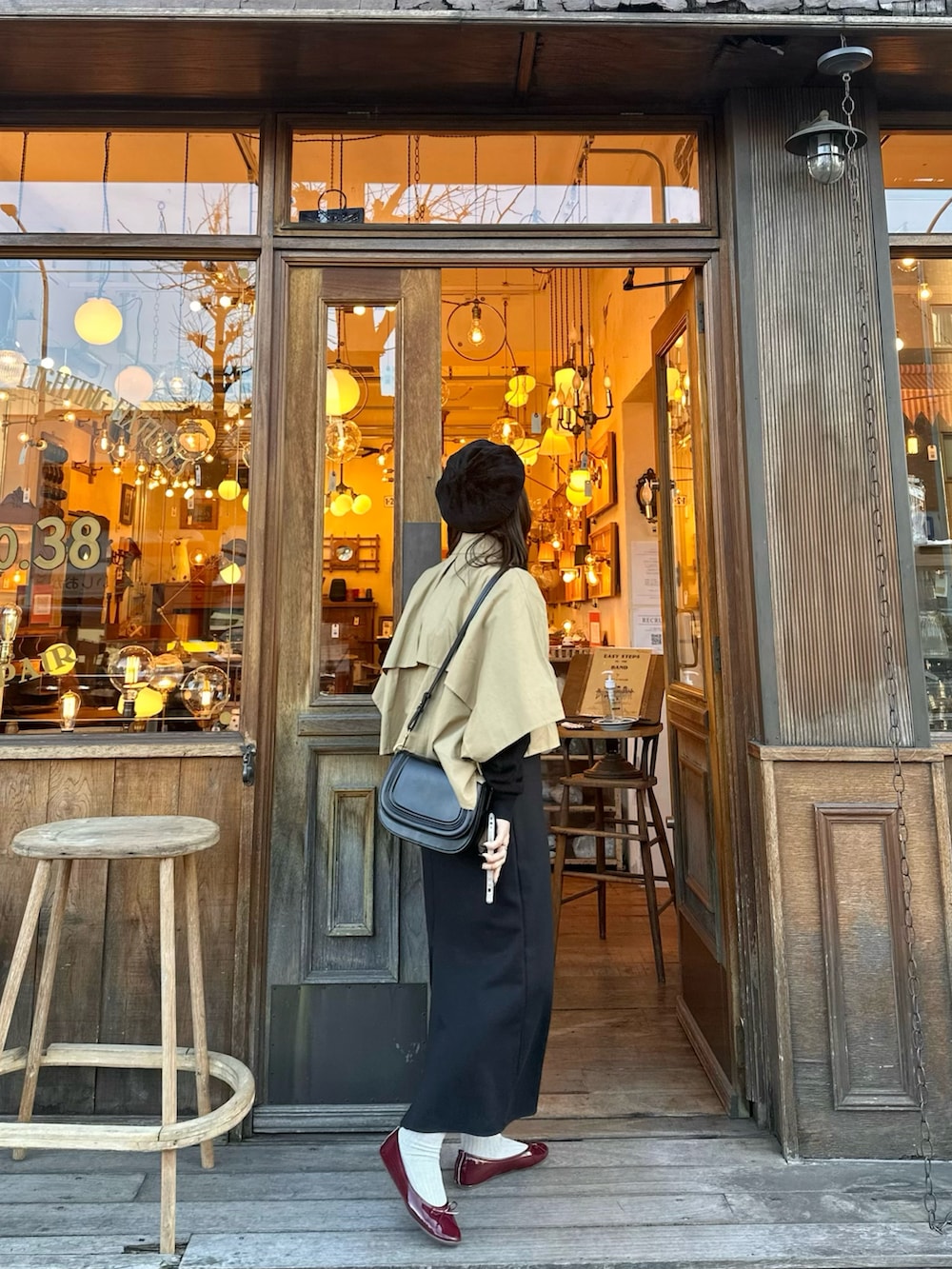 ベージュ系のトレンチコート、ブラック系のショルダーバッグ、ブラック系のスカートを着用したレディースの冬コーディネートの2枚目の写真