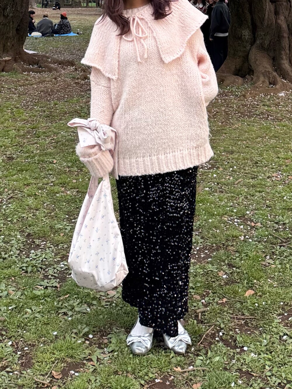 ブラック系のスカート、シルバー系のパンプス、ピンク系のパーカーを着用したレディースの春コーディネートの2枚目の写真