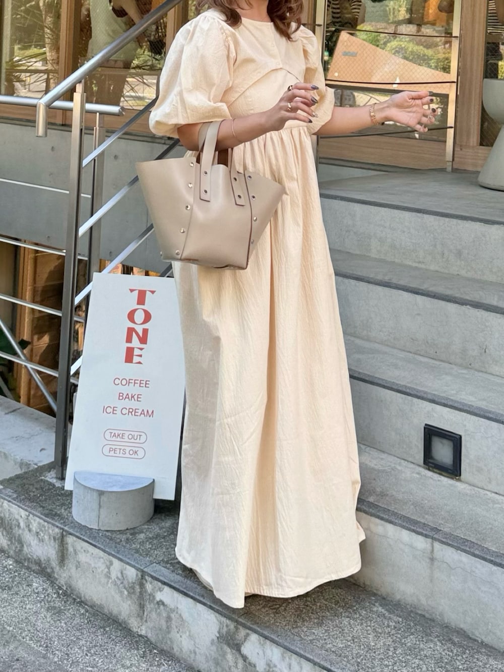 ベージュ系のハンドバッグ、ホワイト系のワンピース、ベージュ系のサンダルを着用したレディースの夏コーディネートの4枚目の写真