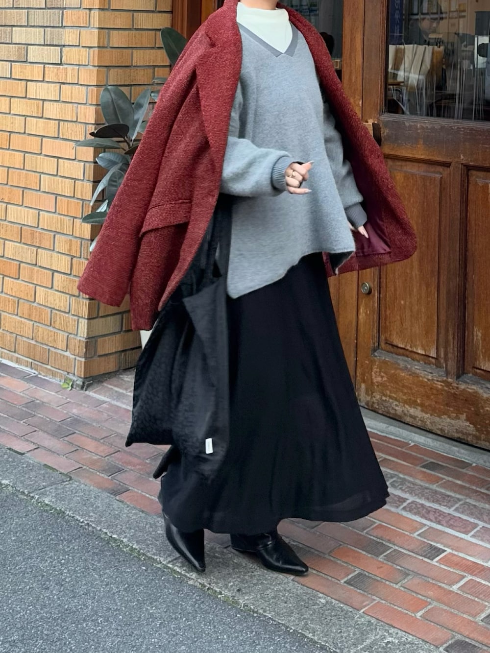 ブラック系のトートバッグ、ブラック系のブーツ、グレー系のニット/セーターを着用したレディースの春コーディネートの2枚目の写真