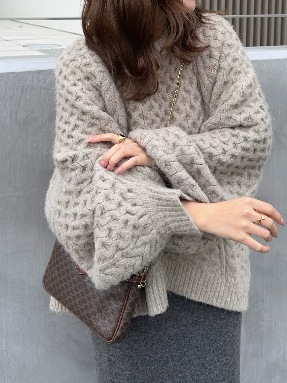 グレー系のスカート、ブラウン系のニット/セーター、シルバー系のローファーを着用したレディースの春コーディネートの3枚目の写真