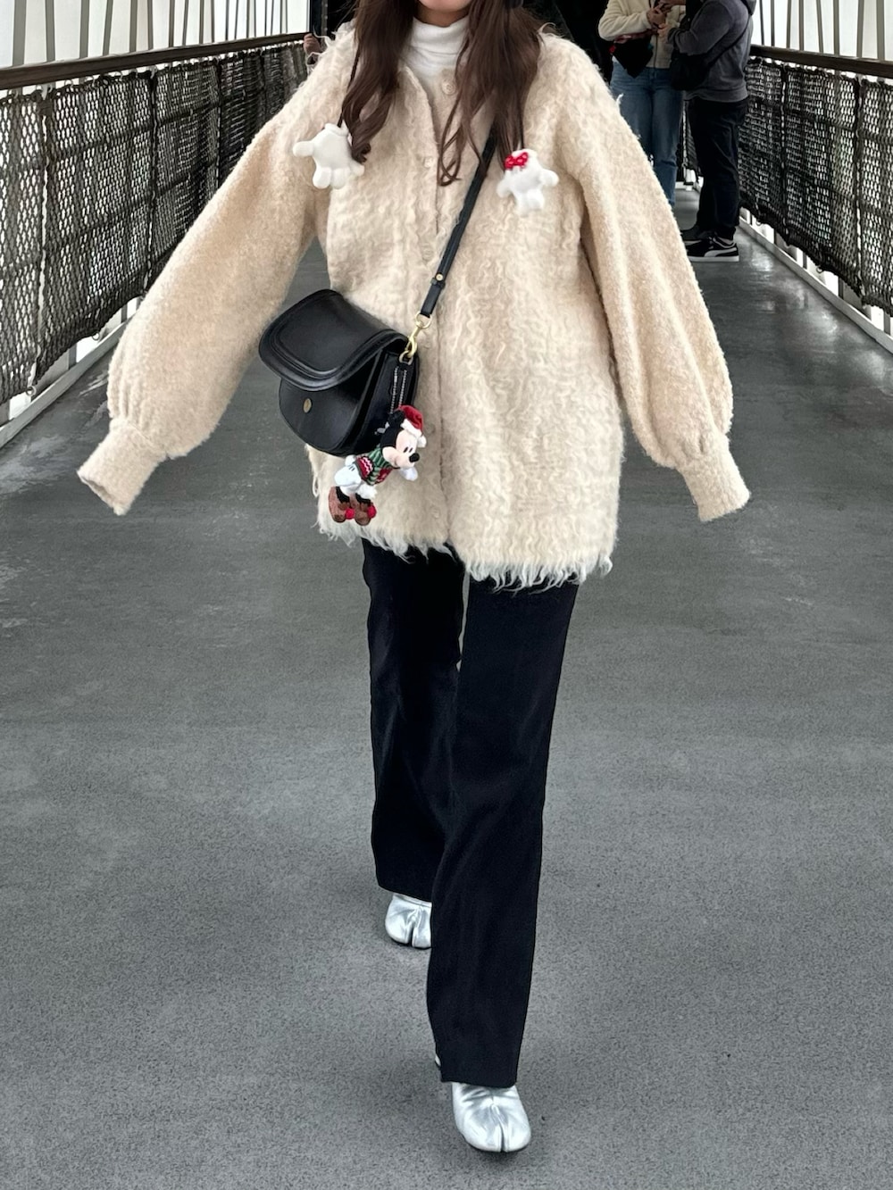 ホワイト系のカーディガン/ボレロ、ブラック系のその他パンツ、シルバー系のブーツを着用したレディースの冬コーディネートの2枚目の写真