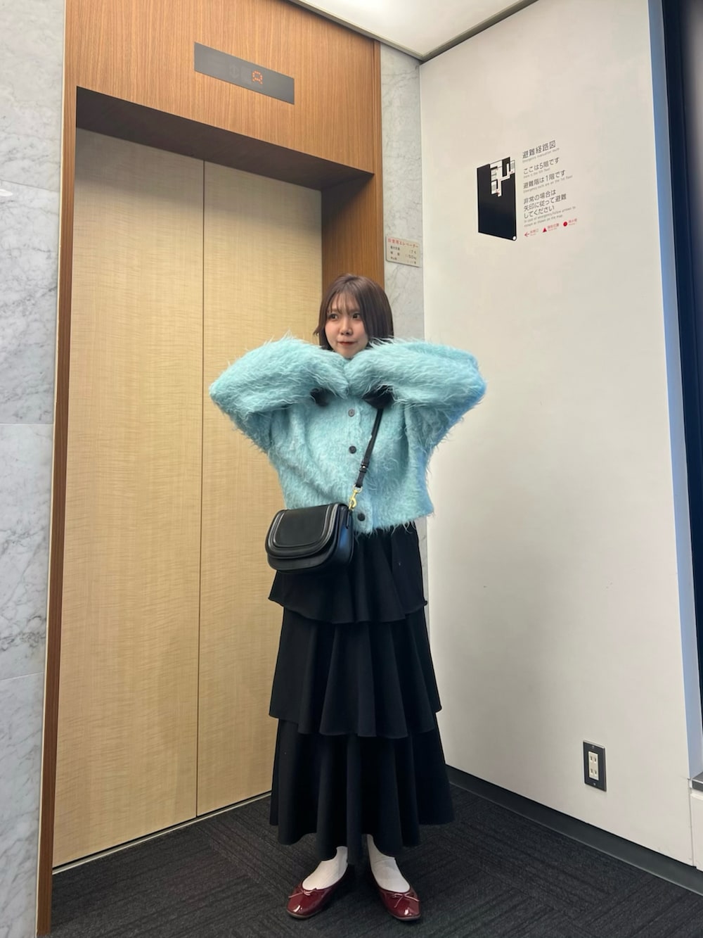 レッド系のバレエシューズ、ブラック系のショルダーバッグ、ブルー系のカーディガン/ボレロを着用したレディースの冬コーディネートの3枚目の写真