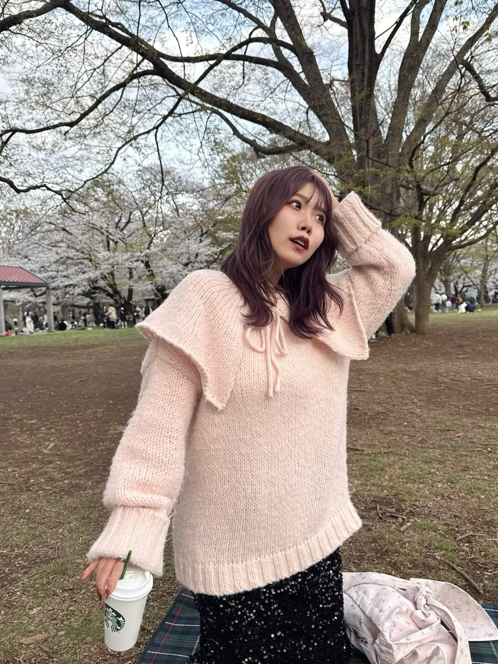 ブラック系のスカート、シルバー系のパンプス、ピンク系のパーカーを着用したレディースの春コーディネートの3枚目の写真