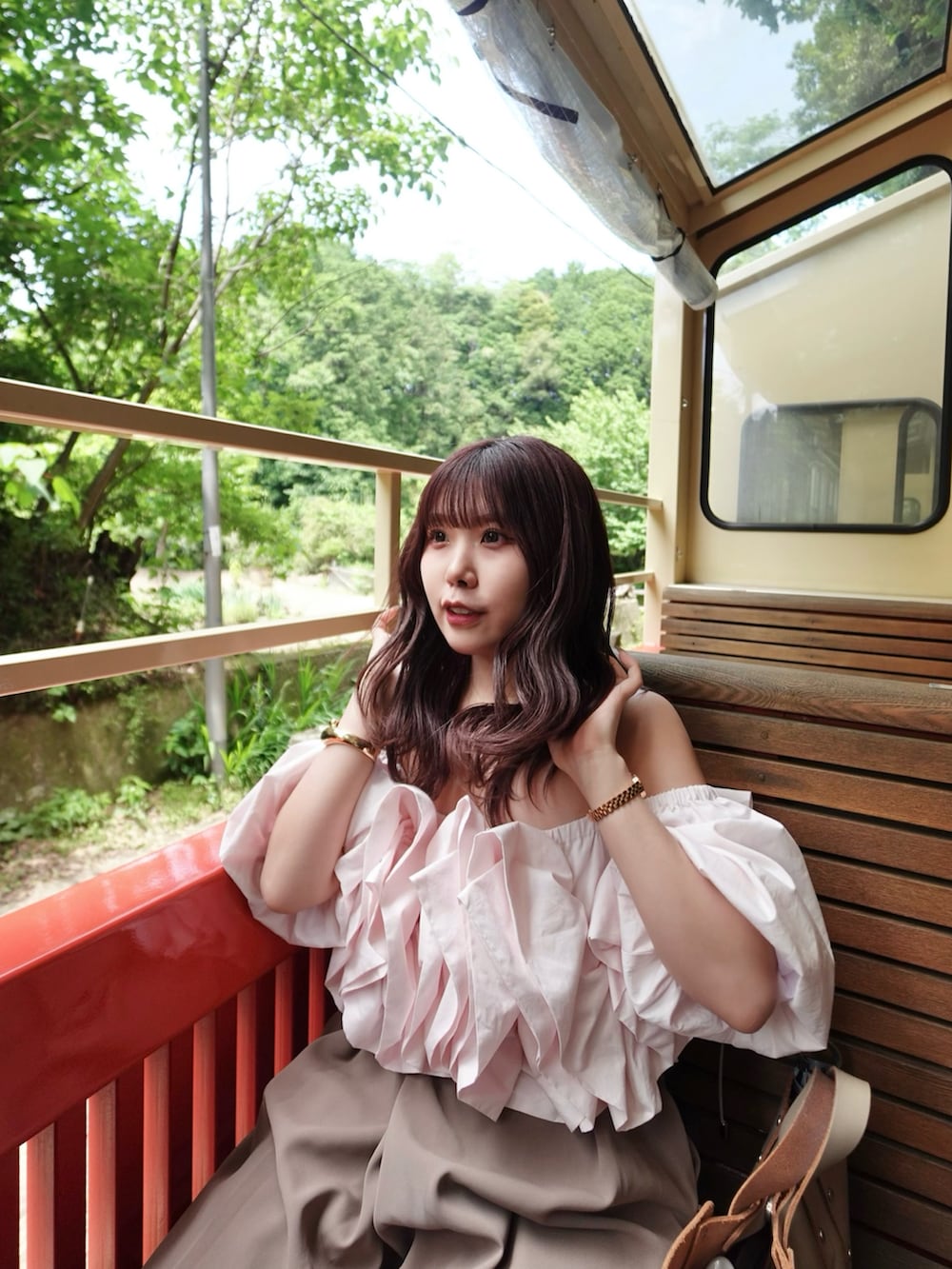 ベージュ系のハンドバッグ、ピンク系のシャツ/ブラウス、ブラウン系のパンツを着用したレディースの夏コーディネートの5枚目の写真