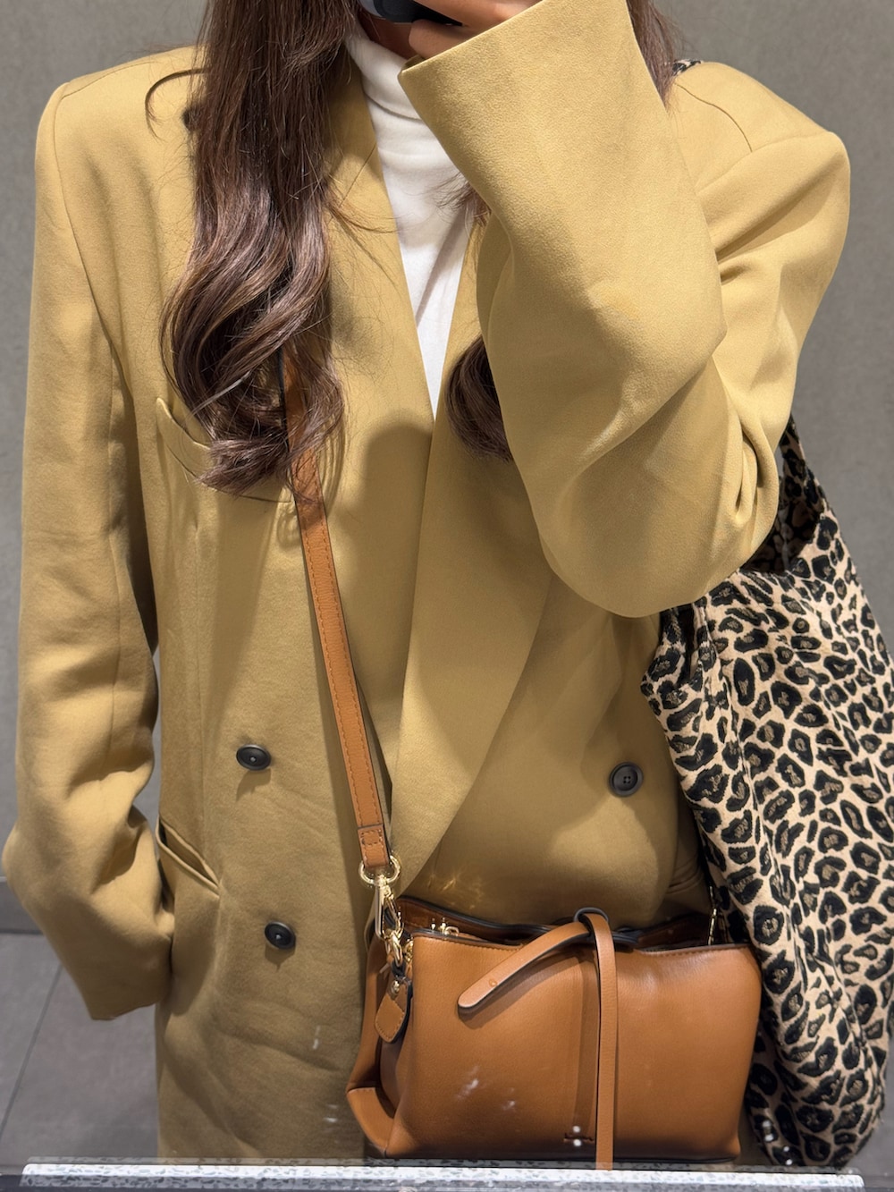 ブラウン系のその他パンツ、イエロー系のショルダーバッグ、ベージュ系のその他アウターを着用したレディースの冬コーディネートの2枚目の写真