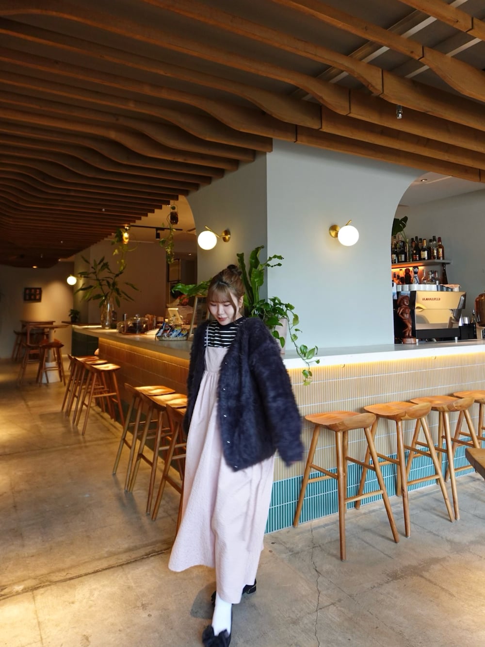 ピンク系のワンピース、ブラック系のパンプス、ブラック系のニット/セーターを着用したレディースの春コーディネートの4枚目の写真