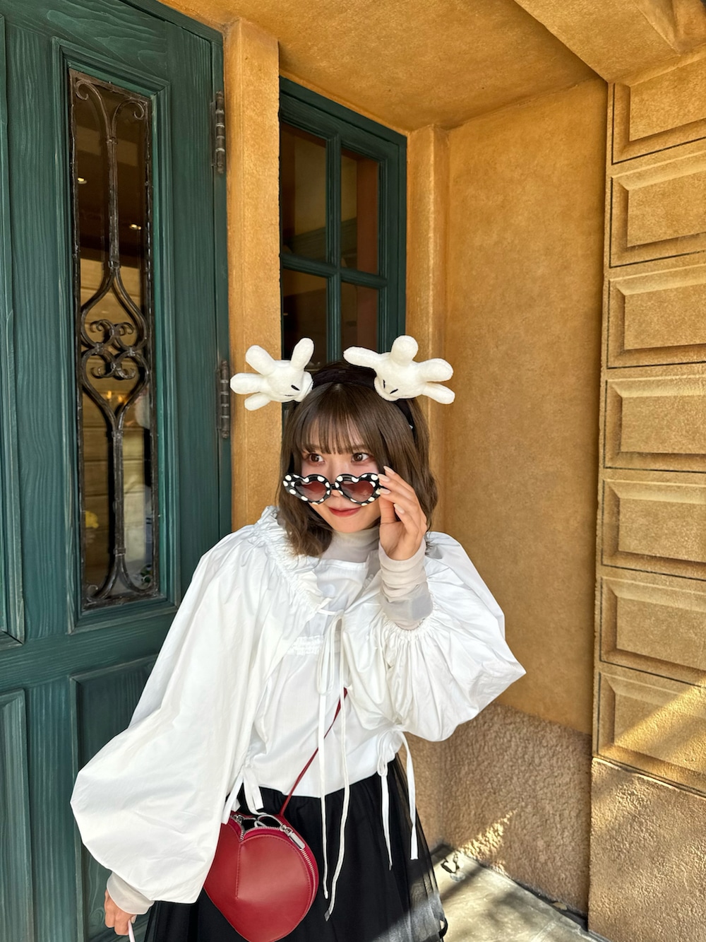 ブラック系のスカート、レッド系のバッグ、ホワイト系のシャツ/ブラウスを着用したレディースの夏コーディネートの4枚目の写真