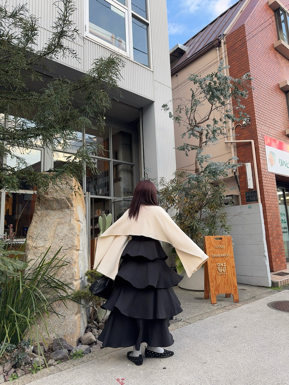 ベージュ系のトップス、ブラック系のスカート、ブラック系のパンプスを着用したレディースの春コーディネートの3枚目の写真