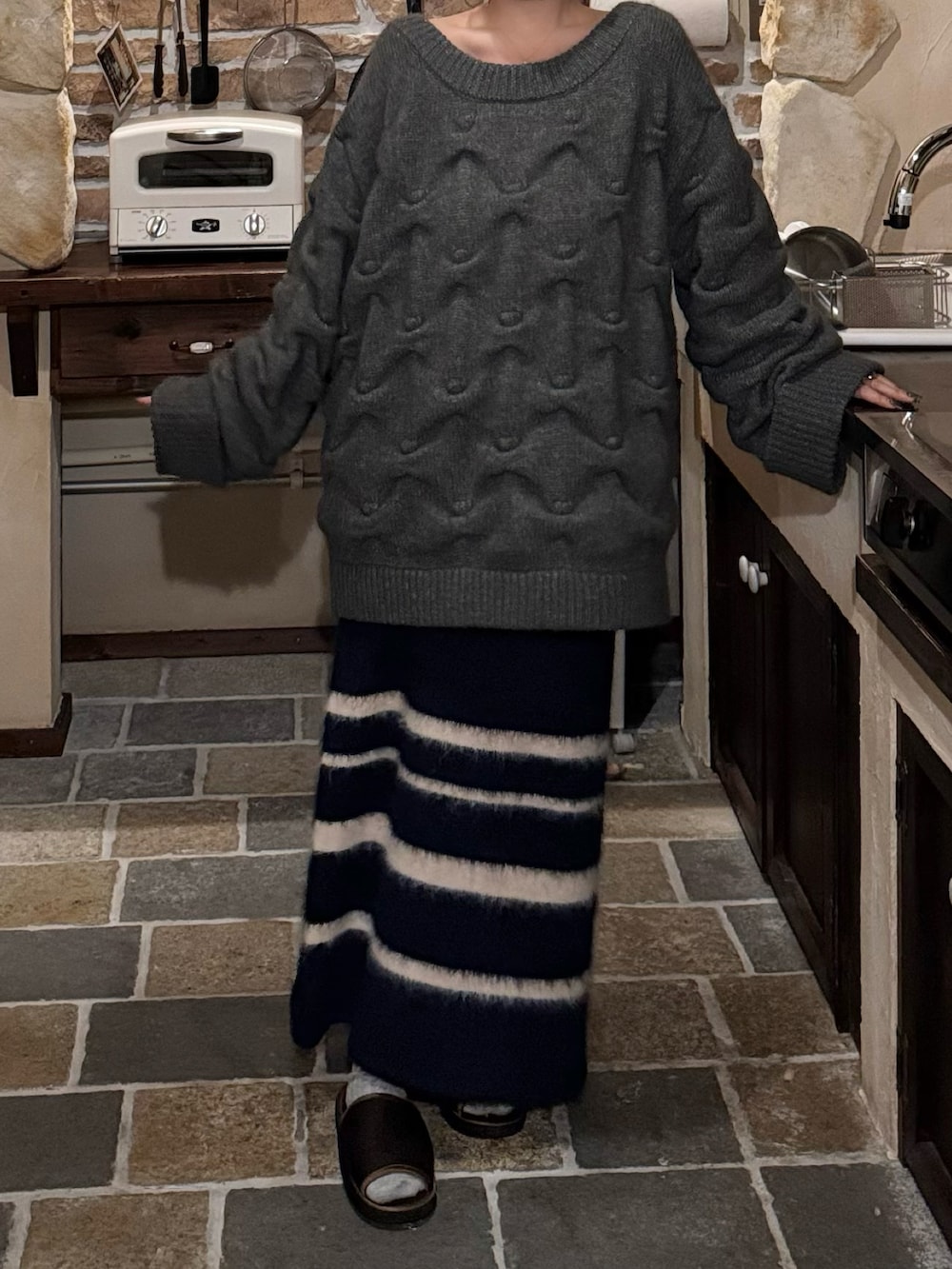 グレー系のニット/セーター、ブルー系のスカートを着用したレディースの冬コーディネートの2枚目の写真