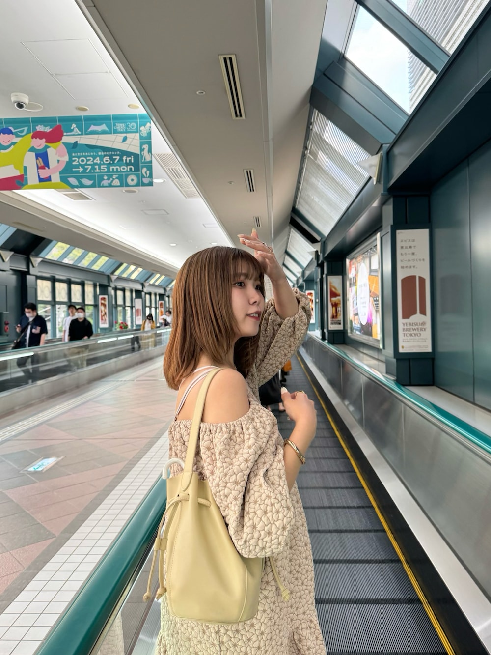 ホワイト系のワンピース、ベージュ系のショルダーバッグ、ブラック系のサンダルを着用したレディースの夏コーディネートの2枚目の写真