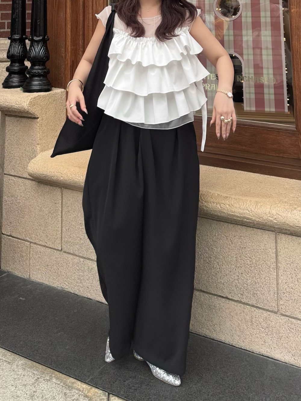 ブラック系のスラックス、シルバー系のローファー、ホワイト系のシャツ/ブラウスを着用したレディースの夏コーディネートの2枚目の写真