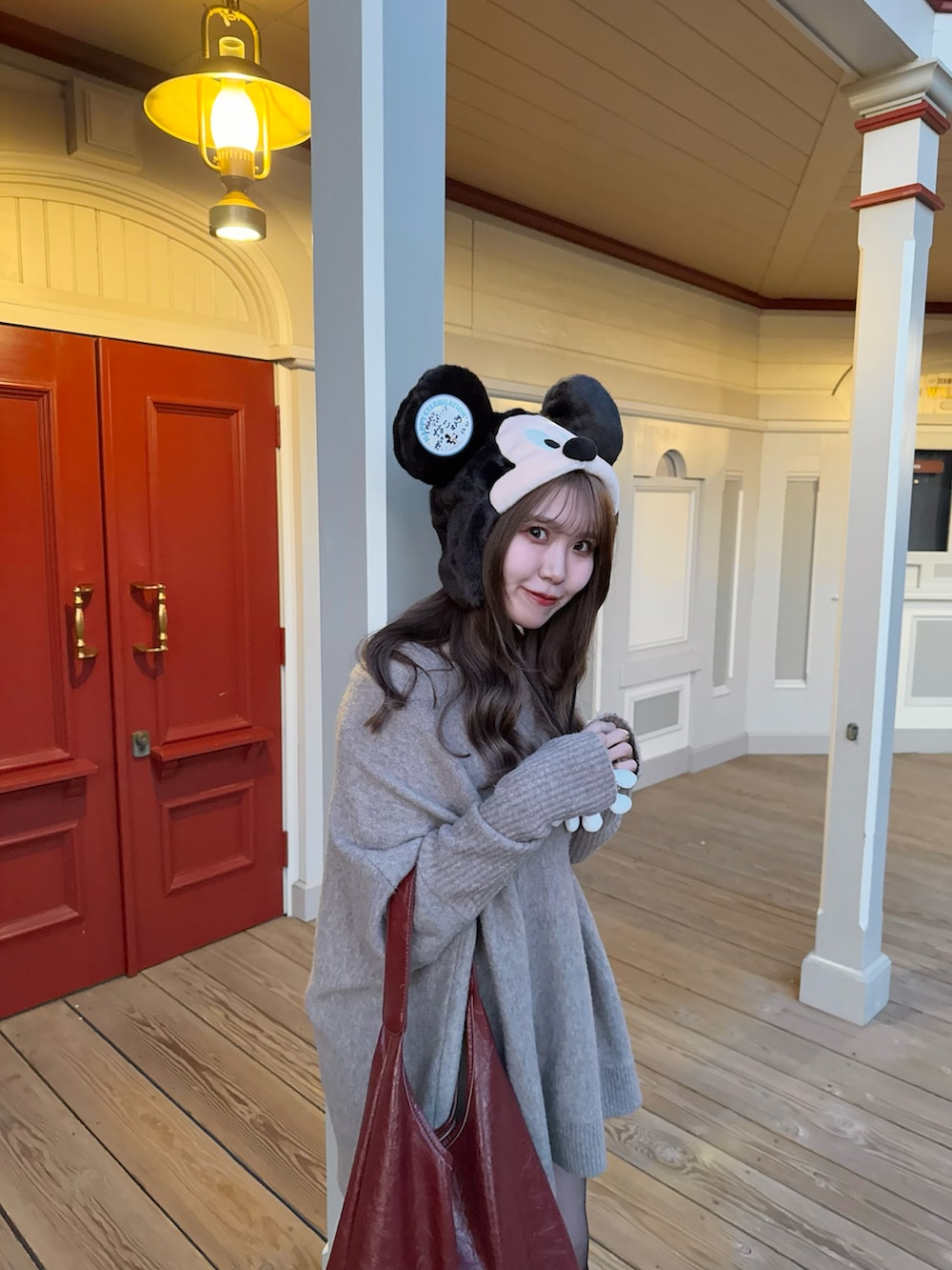 ベージュ系のニット/セーター、レッド系のトートバッグ、ブラック系のブーツを着用したレディースの冬コーディネートの2枚目の写真