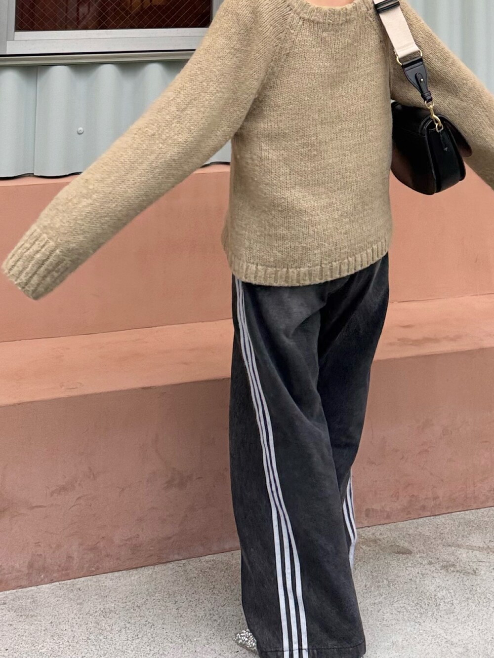 ベージュ系のニット/セーター、ブラック系のデニムパンツ、シルバー系のローファーを着用したレディースの春コーディネートの3枚目の写真