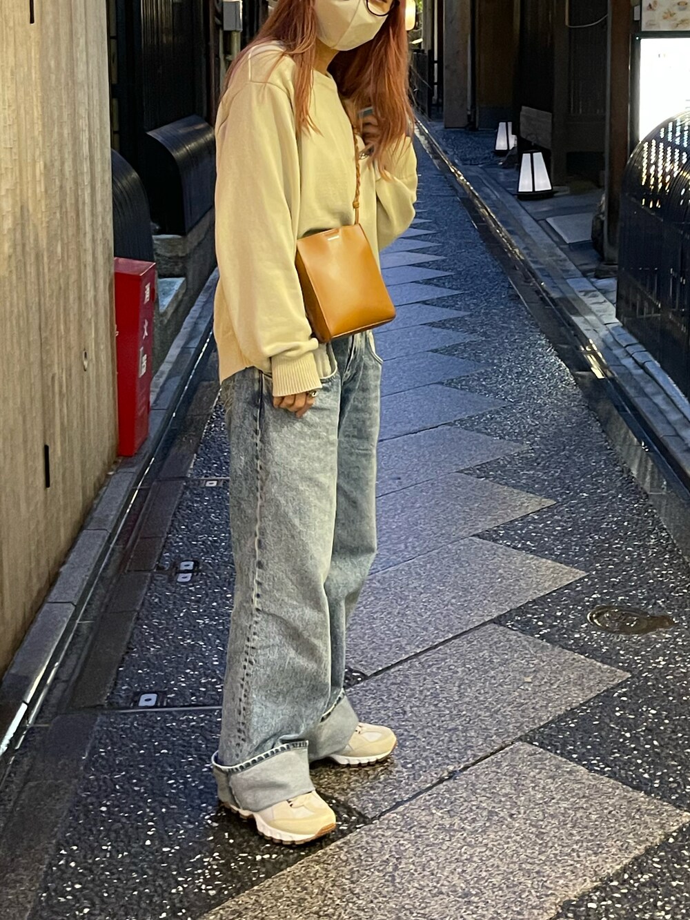 ベージュ系のニット/セーター、ブルー系のデニムパンツ、ベージュ系のスニーカーを着用したレディースの秋コーディネートの2枚目の写真