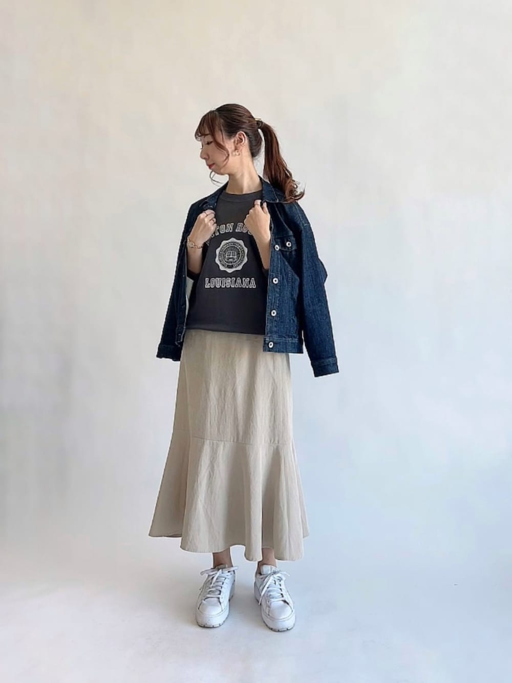 グレー系のスウェット、ベージュ系のスカート、ホワイト系のスニーカーを着用したレディースの冬コーディネートの2枚目の写真