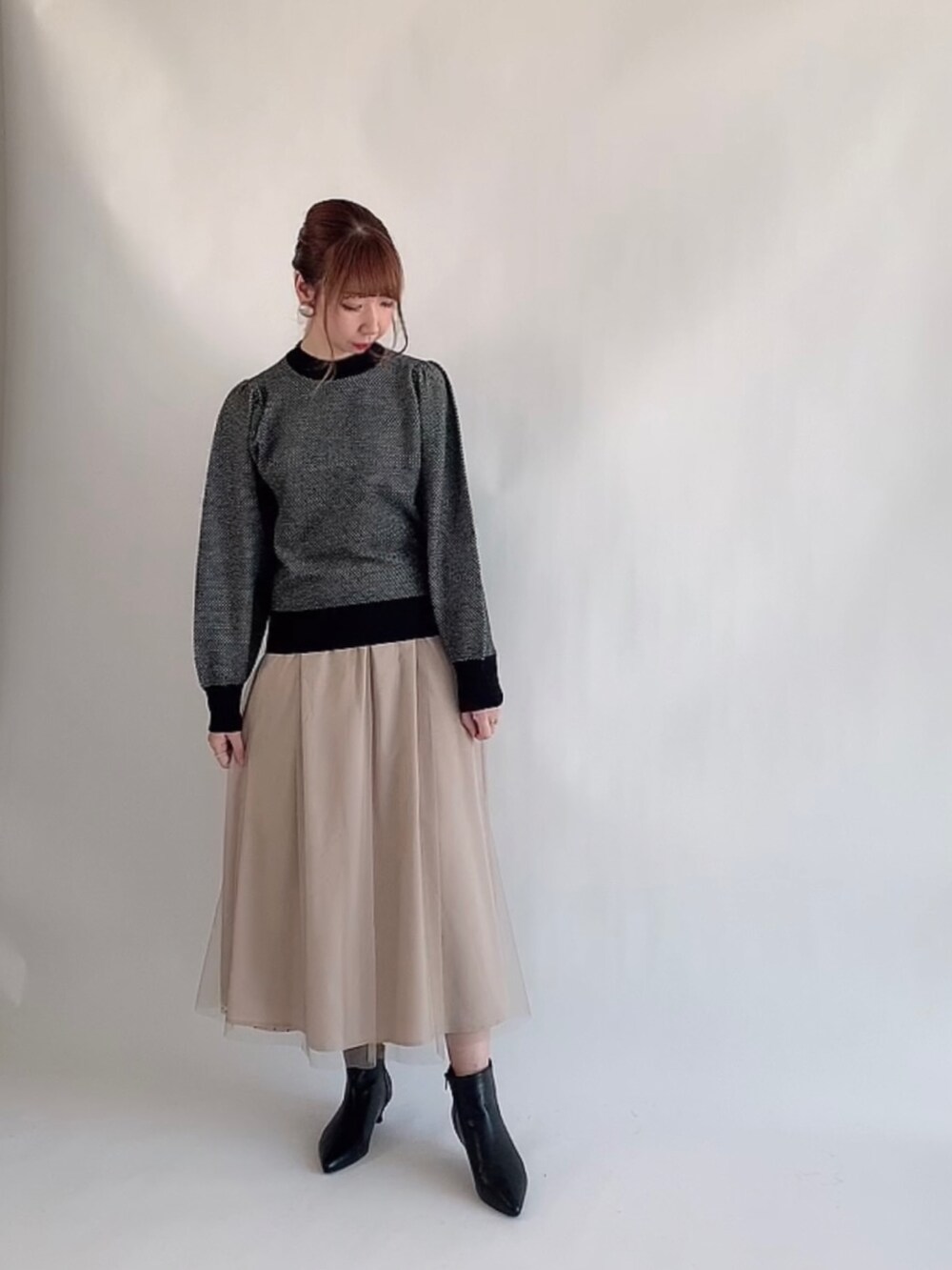ベージュ系のニット/セーター、ブラック系のスカート、ベージュ系のブーツを着用したレディースの冬コーディネートの2枚目の写真