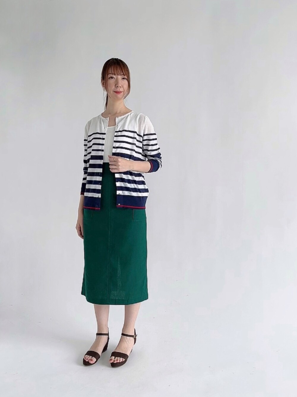 グレー系のカーディガン/ボレロ、イエロー系のスカート、ブラック系のショルダーバッグを着用したレディースの夏コーディネートの2枚目の写真