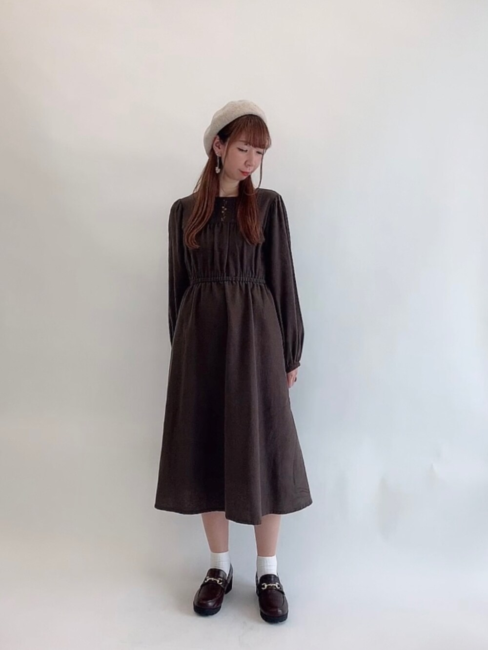 グレー系のワンピース、ホワイト系のハンチング/ベレー帽、ピンク系のその他を着用したレディースの冬コーディネートの2枚目の写真