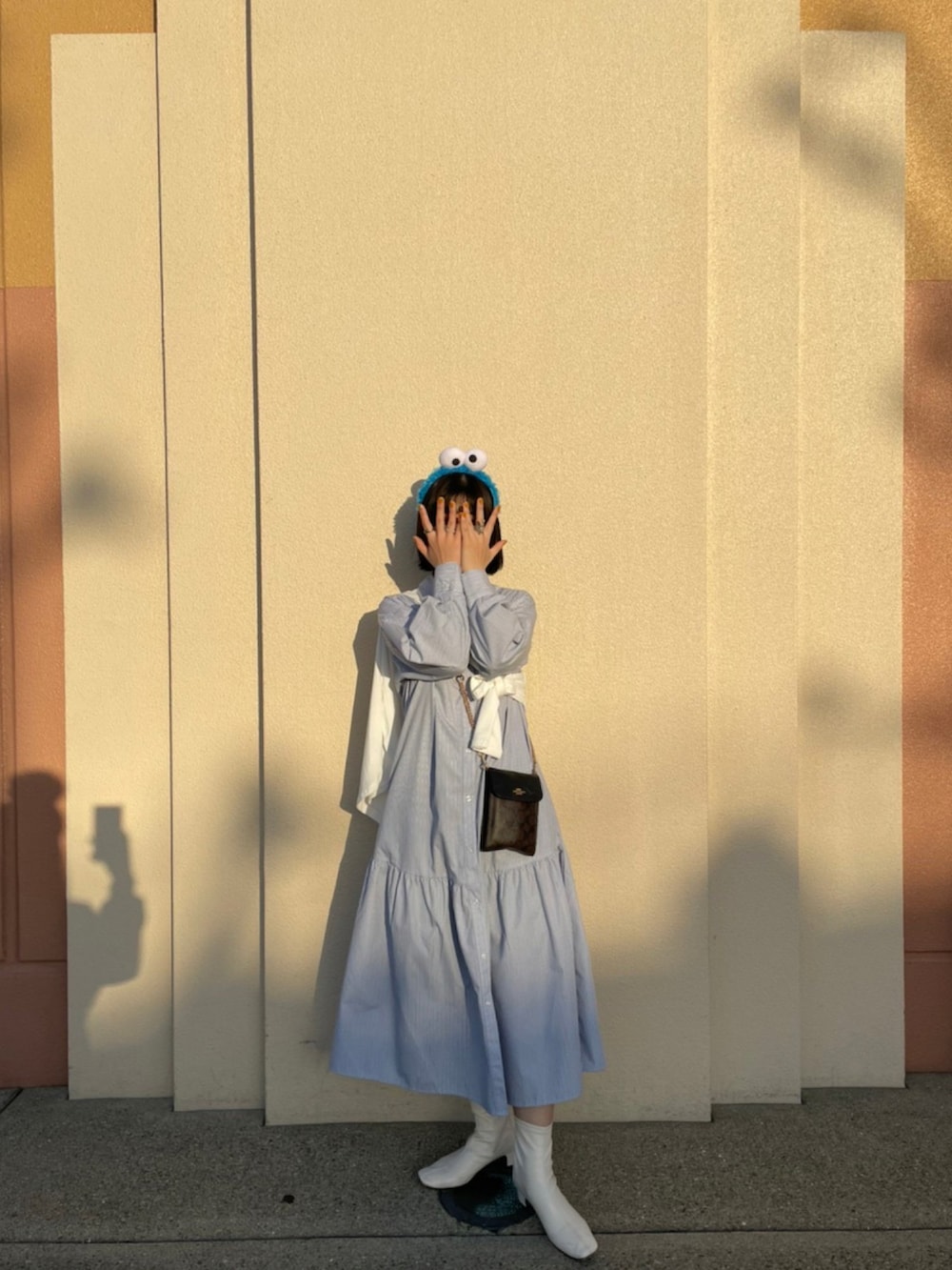 ブルー系のシャツワンピース、ホワイト系のTシャツ/カットソー、ホワイト系のブーツを着用したレディースの春コーディネートの2枚目の写真