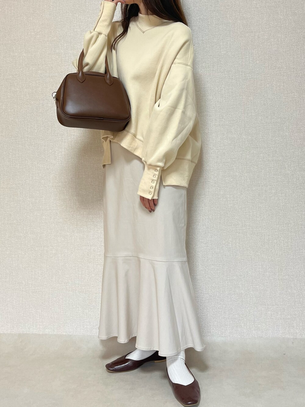 ホワイト系のスウェット、ホワイト系のスカート、ブラウン系のパンプスを着用したレディースの秋コーディネートの2枚目の写真